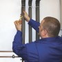 Mann isoliert Heizungsrohr mit selbstklebender Climapor Rohrisolierung PE 18-13.
