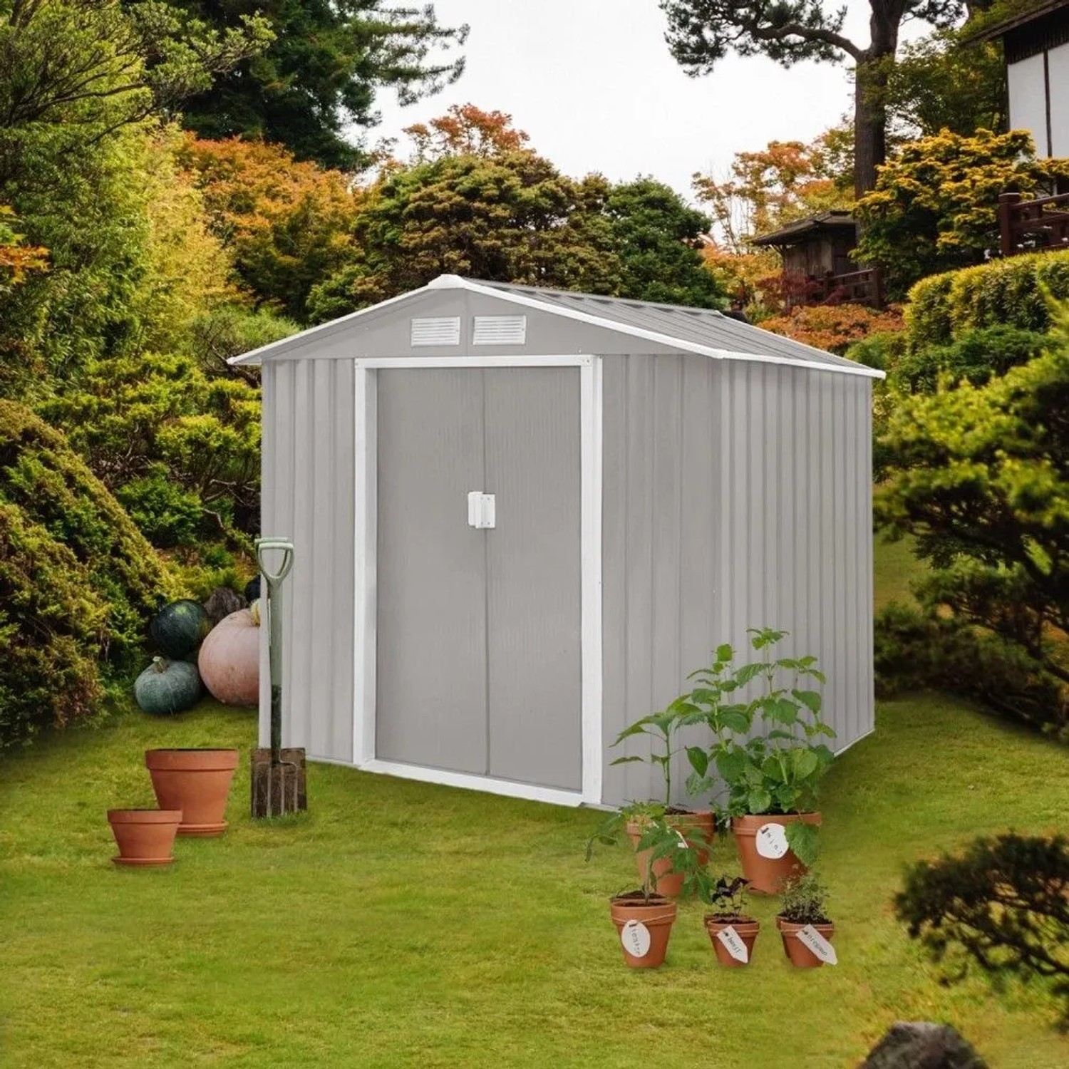 Hattoro S100 Metall Gerätehaus, hellgrau, mit Satteldach und Doppeltür, im grünen Garten mit Pflanzen.