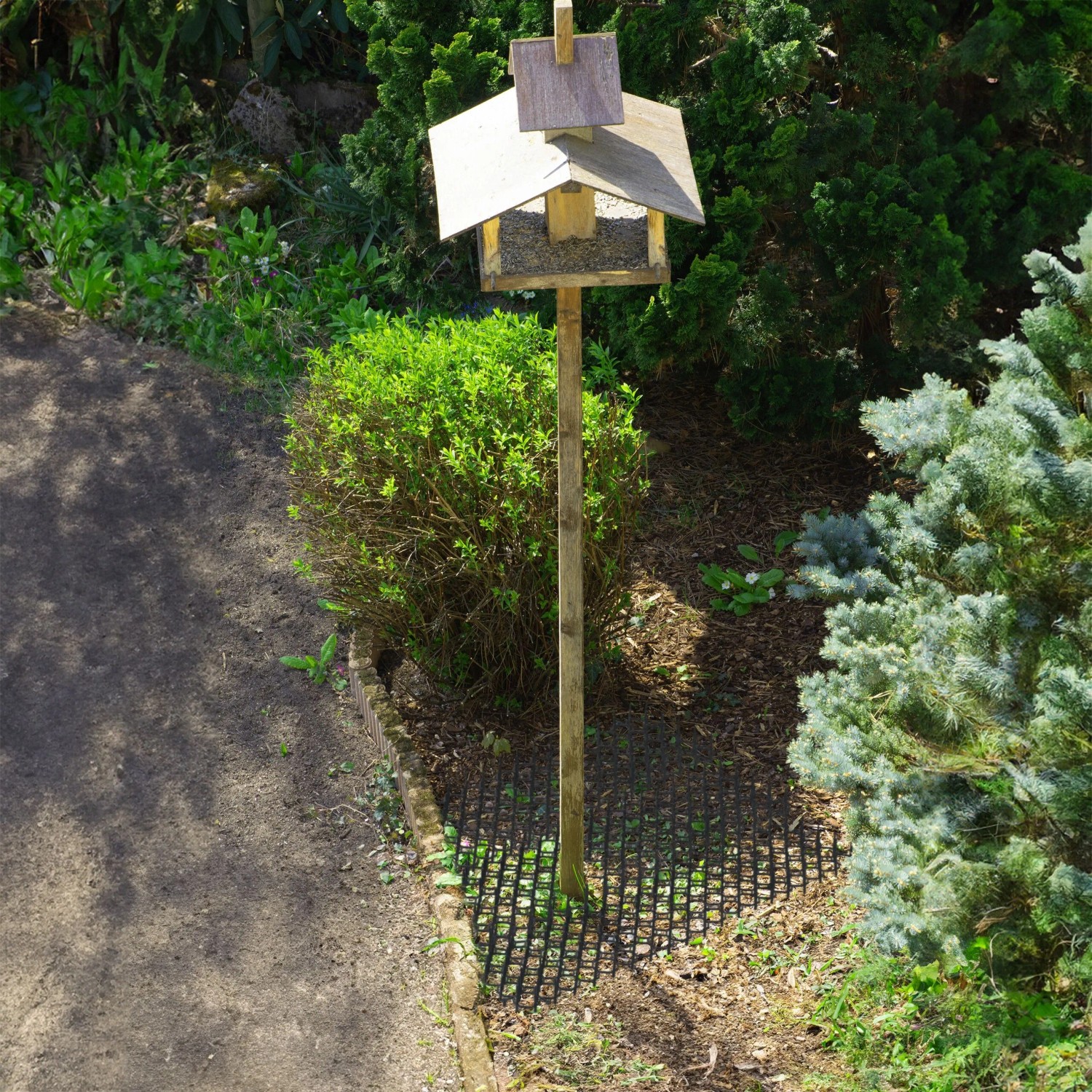Schwarzes Dornengitter-Set (12 Stk.) unter einem Vogelhaus im Garten als Tierabwehr.