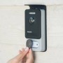 Philips WelcomeEye Connect 2 Video-Türsprechanlage, dunkelgrau/silber, an Wand. Hand nutzt RFID-Tag für Zutritt.