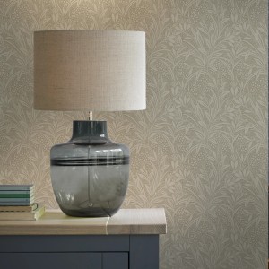 Laura Ashley Vliestapete Barley Natural mit Blätter- und Beerendesign, kombiniert mit einer grauen Lampe.