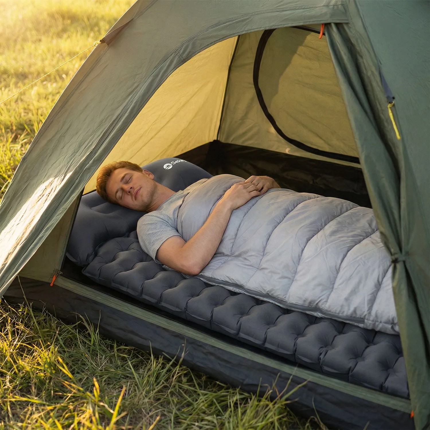 Mann schläft auf grauer Sekey selbstaufblasender Isomatte im Zelt. Komfortable Campingmatte mit integriertem Kopfkissen.