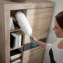 Frau reinigt Bücherregal mit Leifheit Staubwedel Duster XL.