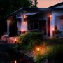 Philips Hue Impress LED-Wandleuchten in breiter Anordnung an Hauswand und Garten.