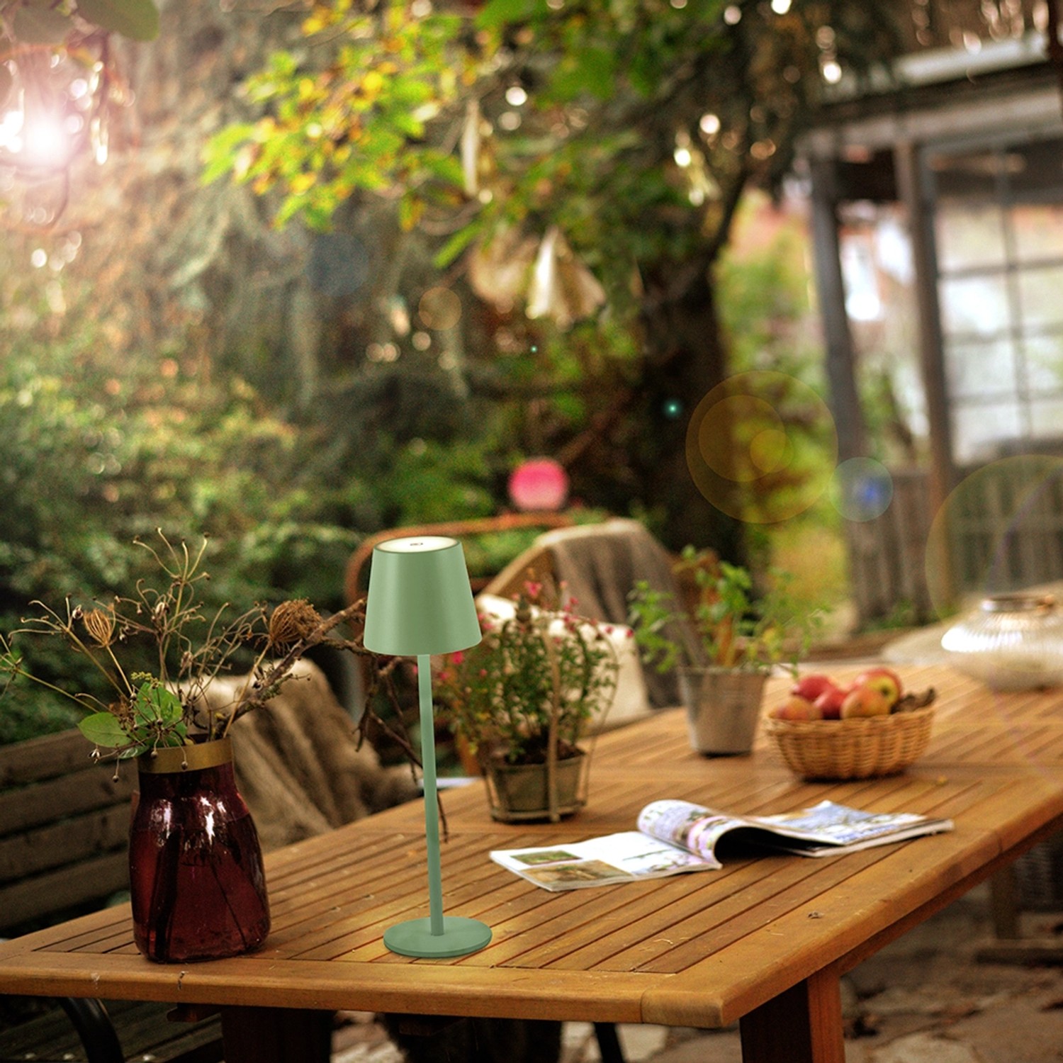 Grüne LED-Akku-Tischleuchte Euria von Just Light auf einem Gartentisch. Dekorative Außenleuchte.