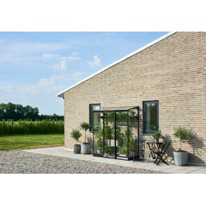 Schwarzes Halls Anlehngewächshaus Qube Lean-to 26 mit Pflanzen am Haus.