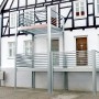 Designbalkon Small mit Holzfußboden und Lamellengeländer am Haus montiert.