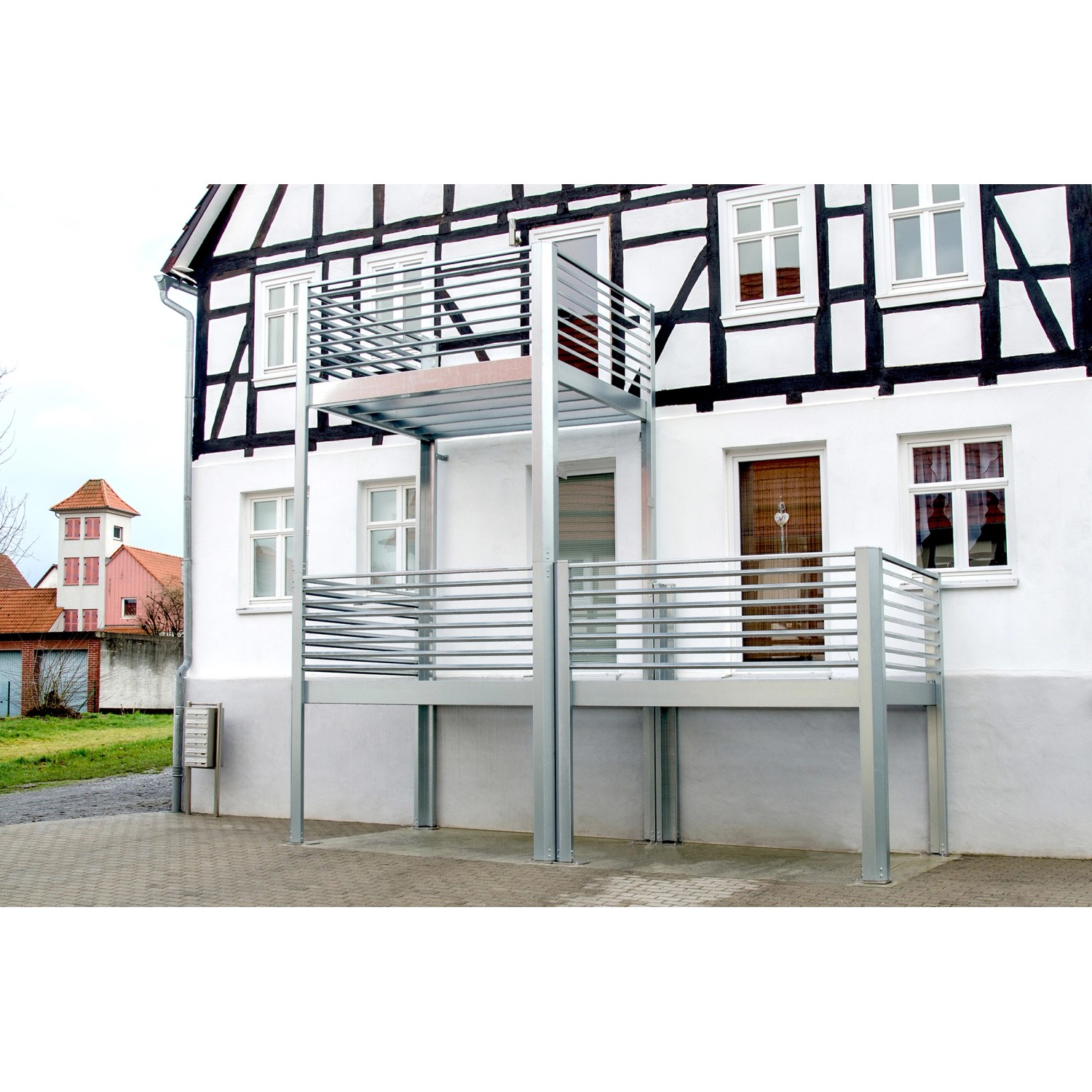Designbalkon Small mit Holzfußboden und Lamellengeländer am Haus montiert.