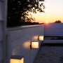 Anthrazitfarbene Lutec Box Cube Außenwandleuchten an einer weißen Wand bei Sonnenuntergang.