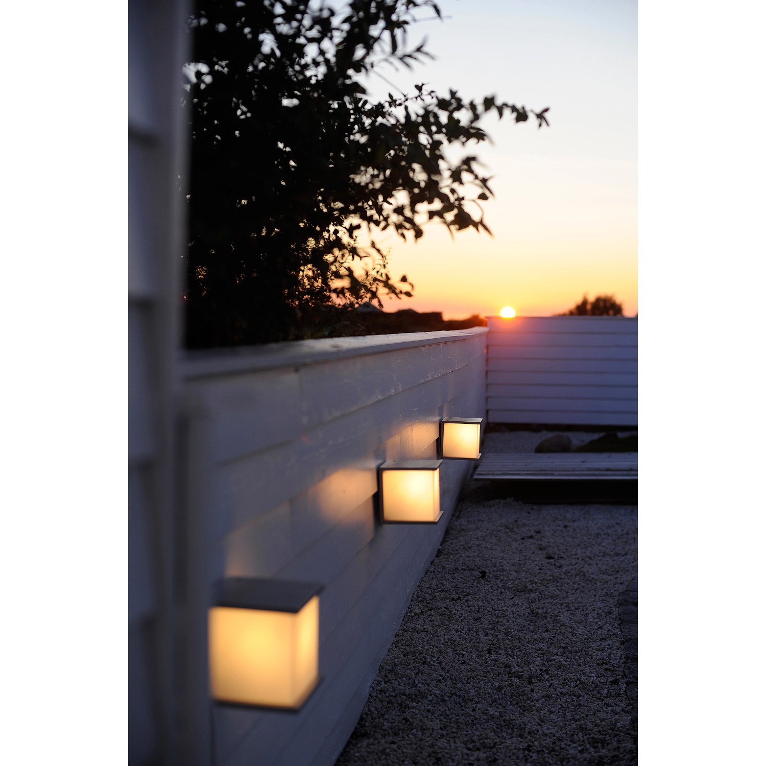 Anthrazitfarbene Lutec Box Cube Außenwandleuchten an einer weißen Wand bei Sonnenuntergang.