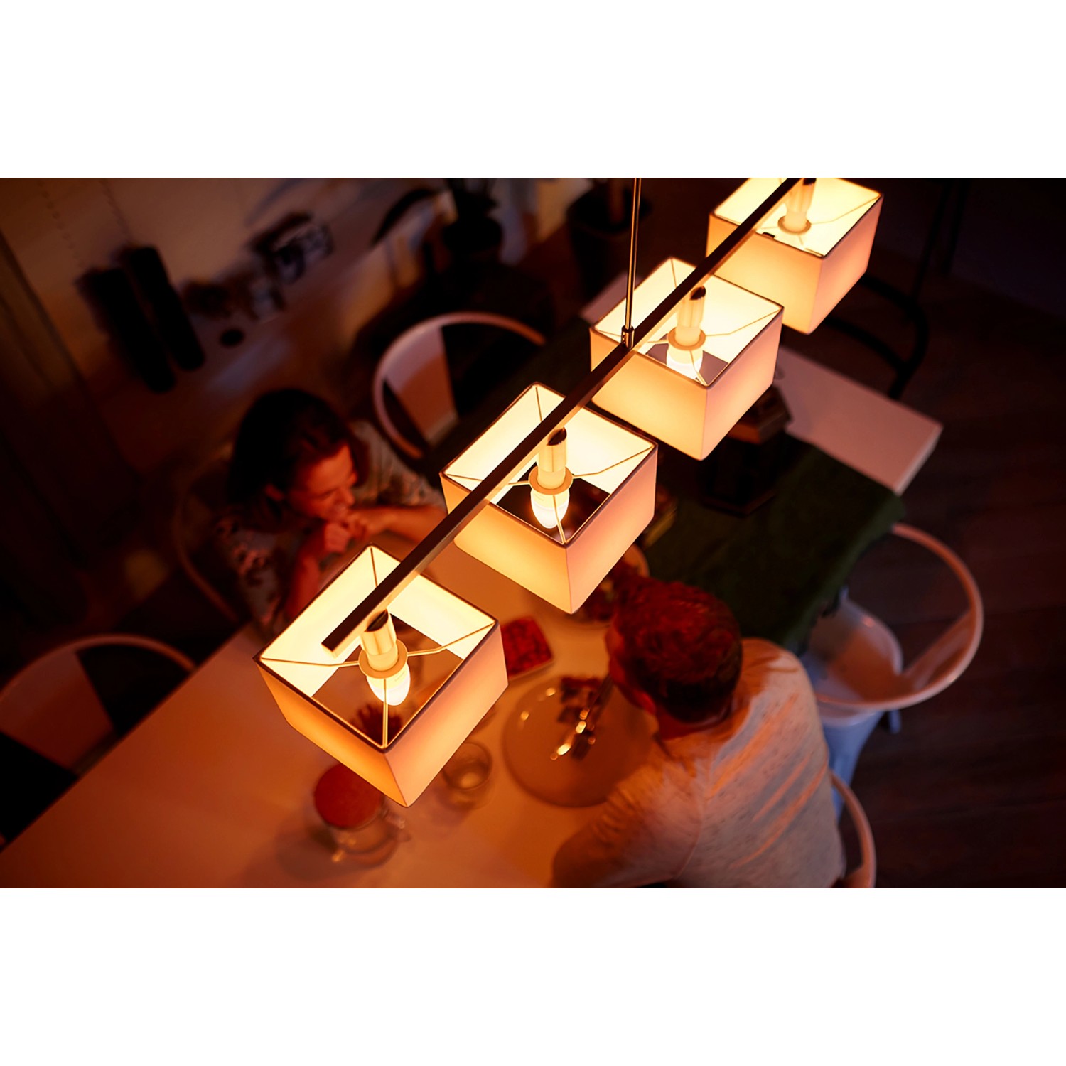 Philips Hue E14 Kerzen-Leuchtmittel im 2er-Pack über Esstisch mit Personen.