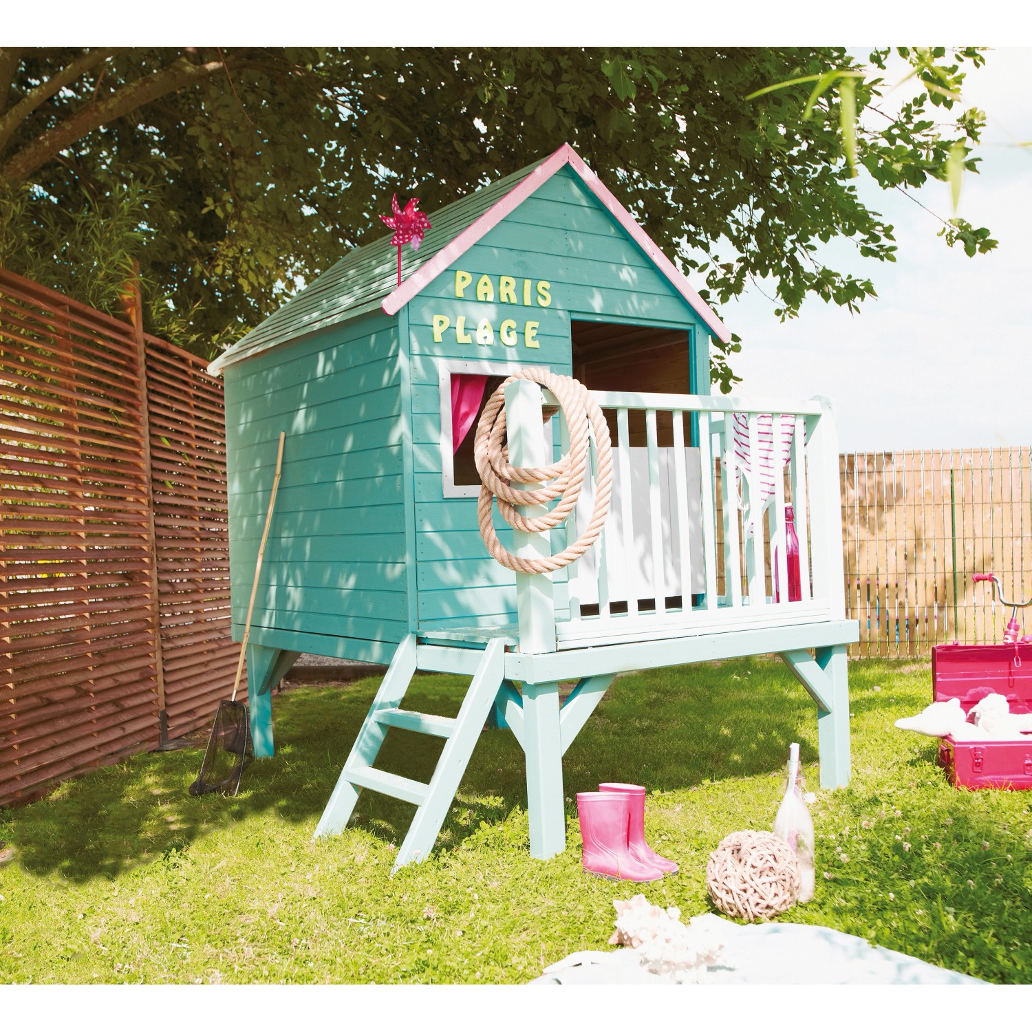 Blaues Soulet Kinderspielhaus Winny mit Leiter und Veranda im Garten.