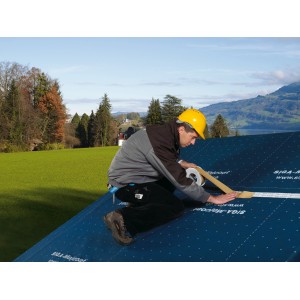 Handwerker verklebt mit Siga Wigluv 60 Klebeband eine Unterspannbahn auf einem Dach.