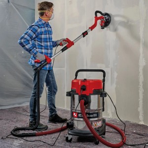 Mann schleift Wand mit Einhell Nass-Trockensauger TE-VC 5090 SACL. Effektive Staubabsaugung auf der Baustelle.