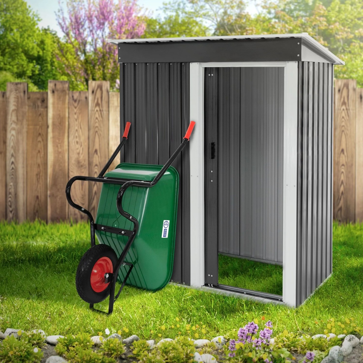 Grüne ECD Germany Gartenschubkarre (100L) mit Luftrad an Gartenhauswand.