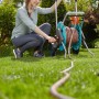 Frau bedient Gardena CleverRoll M Schlauchwagen-Set mit 20m Schlauch im Garten.