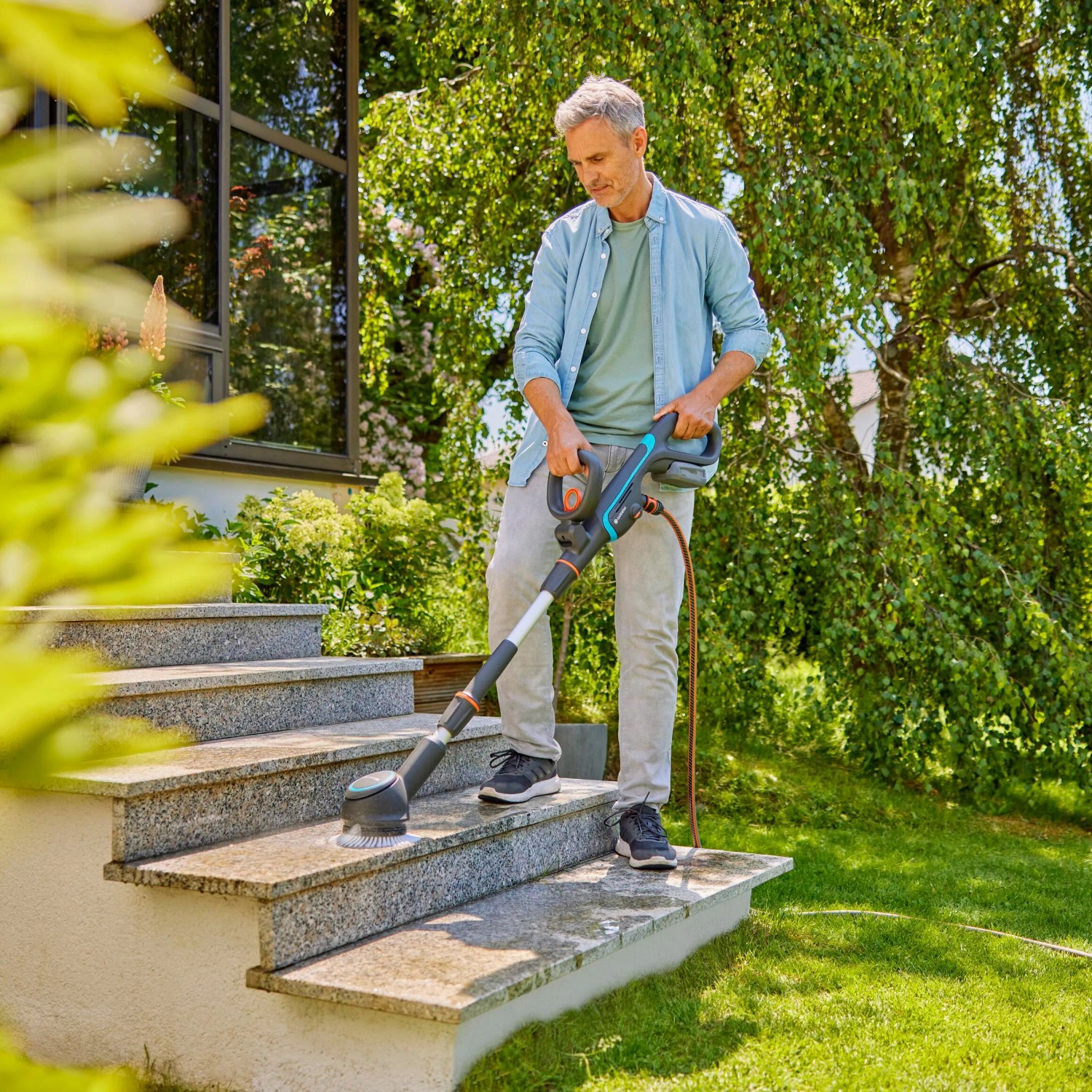 Mann reinigt Steintreppe mit Gardena Akku-Multi-Reiniger AquaBrush Patio. Inkl. Akku.