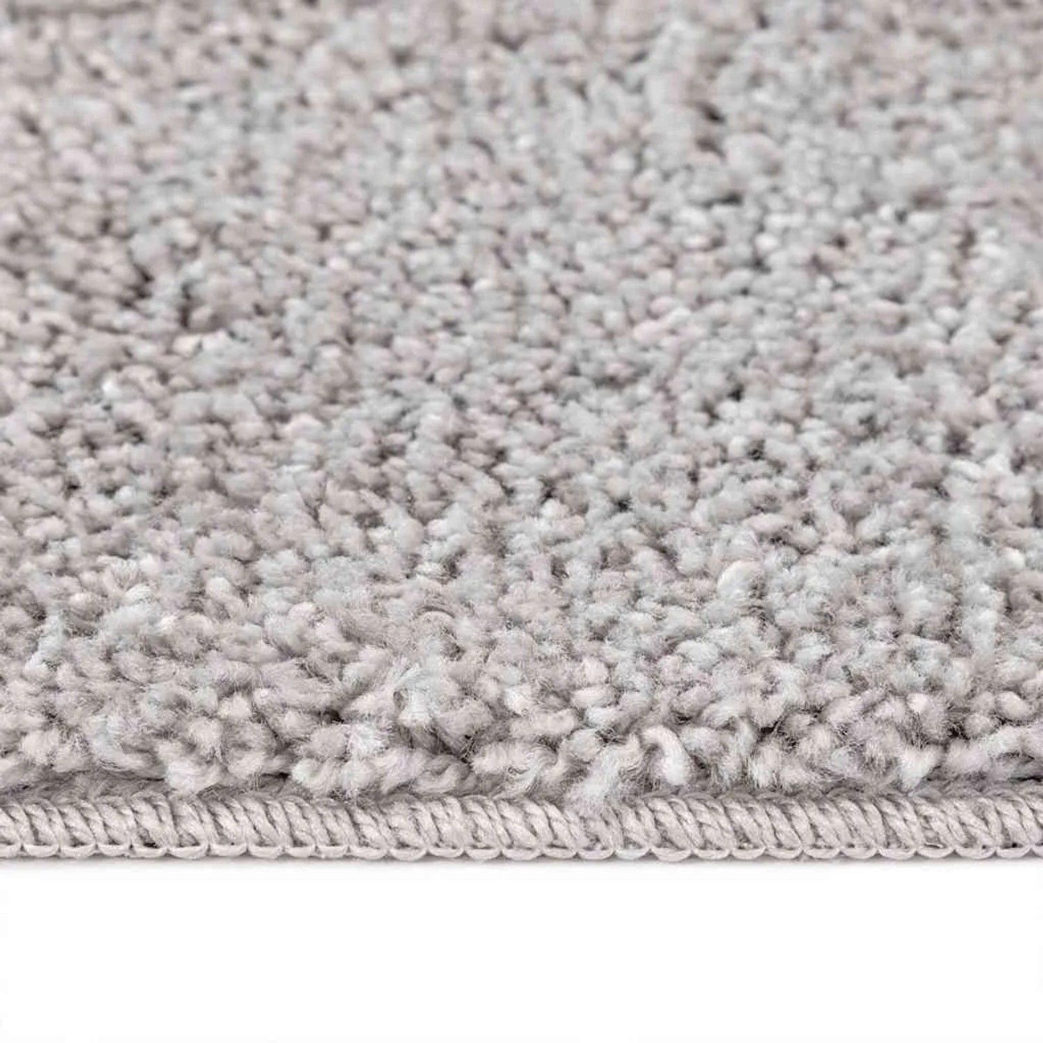 Nahaufnahme eines grauen Hochflorteppichs mit weicher Shaggy-Textur und sauberer Kante. Rutschfester Teppich aus PP.