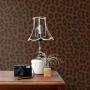 Dekorative Vliestapete mit braunem Leopardenmuster an einer Wand, in einem Raum mit Vintage-Möbeln.