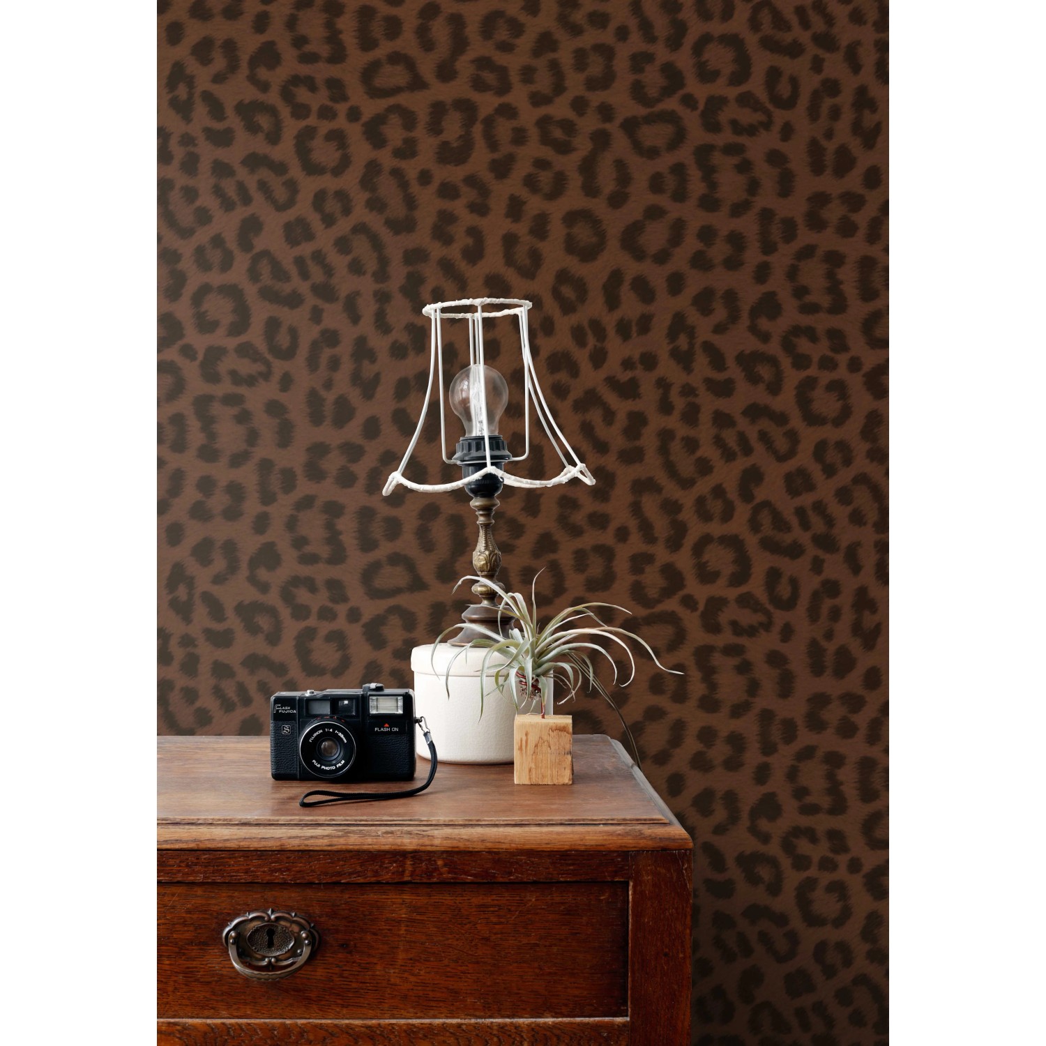 Dekorative Vliestapete mit braunem Leopardenmuster an einer Wand, in einem Raum mit Vintage-Möbeln.