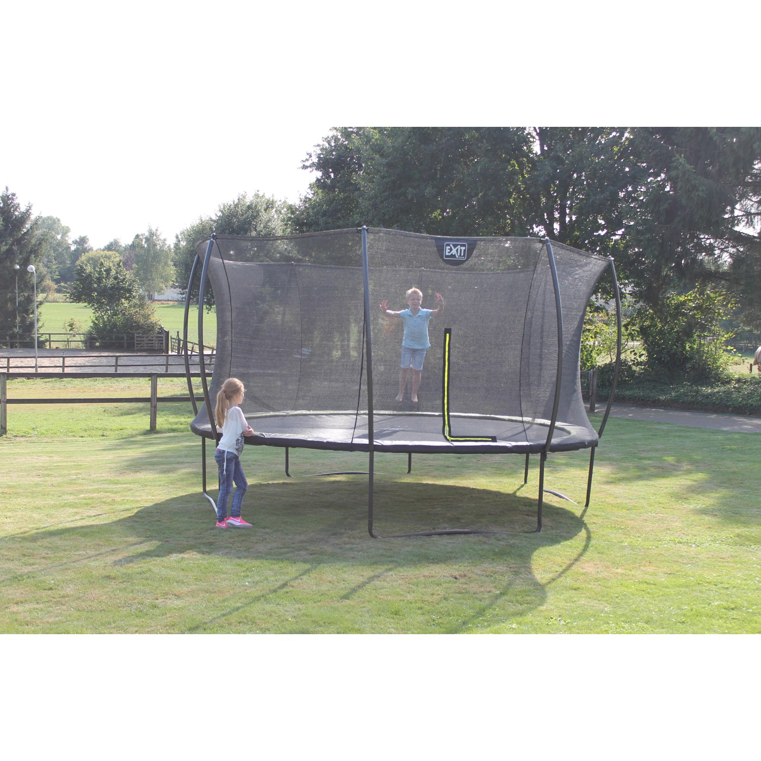 Grünes EXIT Silhouette Trampolin D305cm mit Sicherheitsnetz und Kindern im Garten.