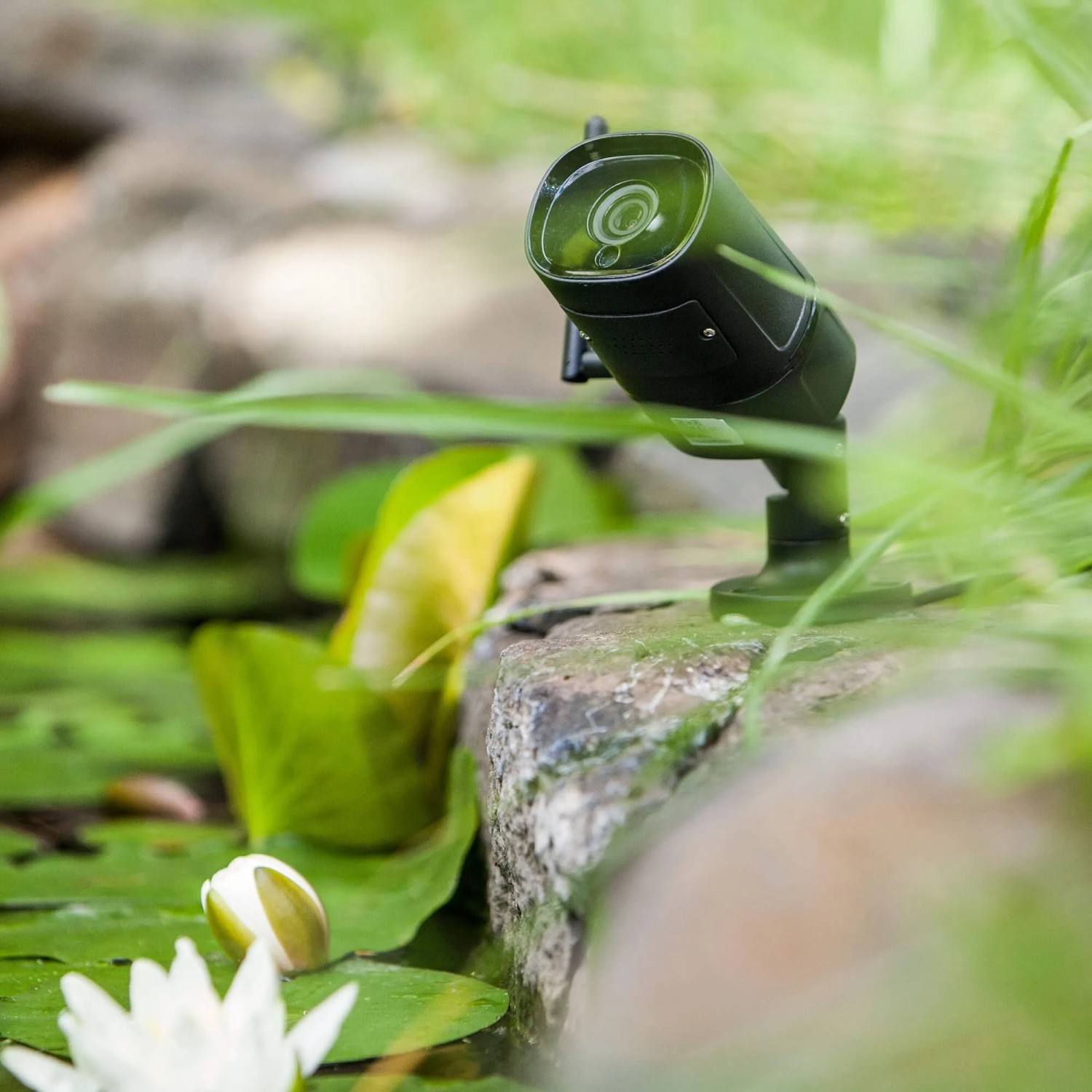Summer Fun Smart Garden Cam Outdoor WiFi Kamera auf Stein mit Pflanzen im Garten.