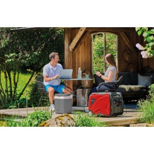 Roter Einhell Stromerzeuger TE-IG 3500 versorgt Laptop & Kühler auf Holzterrasse im Garten. Mobil für Outdoor-Strom.