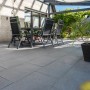 Diephaus Terrassenplatten Rima Basalt, 60x40 cm, auf einer Terrasse mit Gartenmöbeln.
