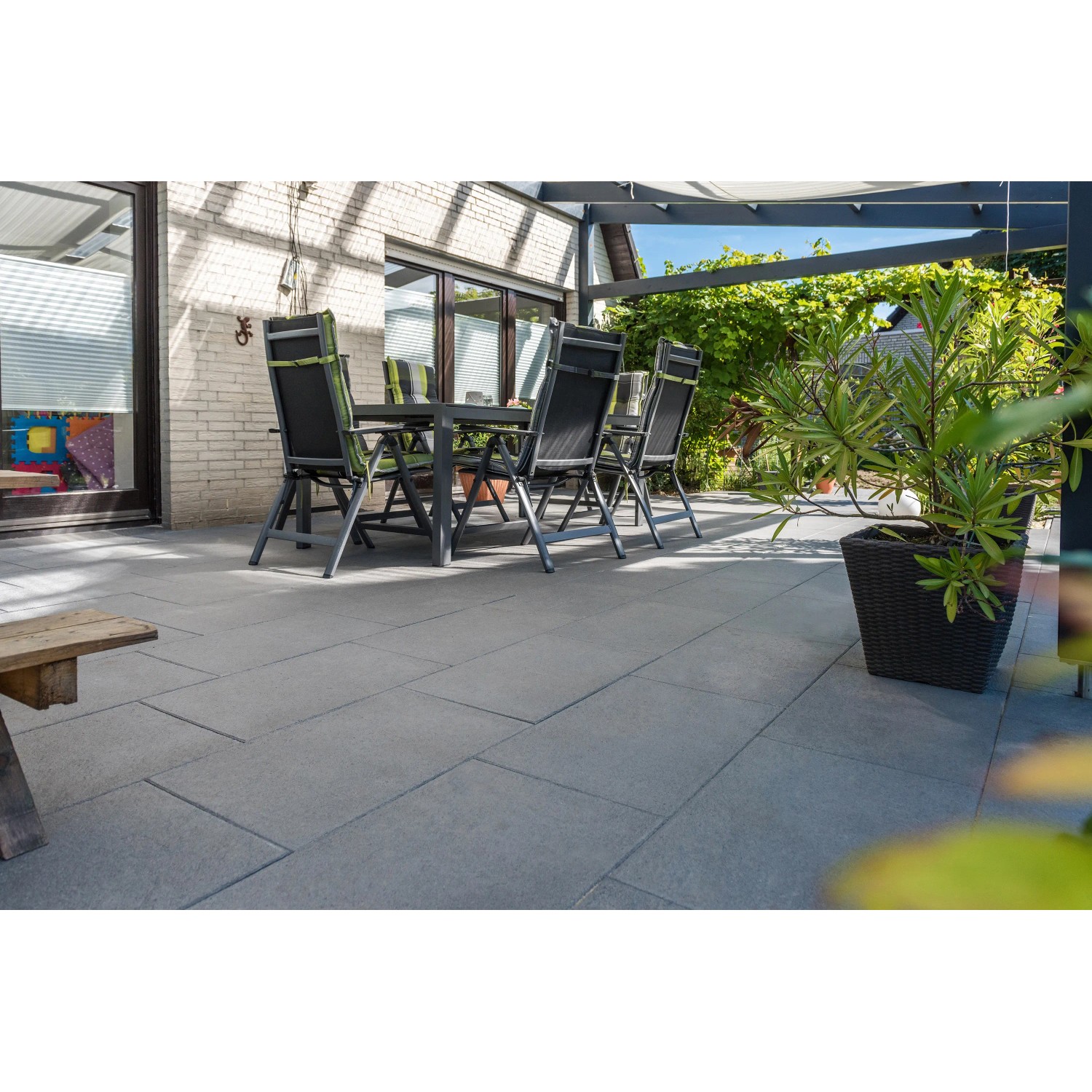 Diephaus Terrassenplatten Rima Basalt, 60x40 cm, auf einer Terrasse mit Gartenmöbeln.