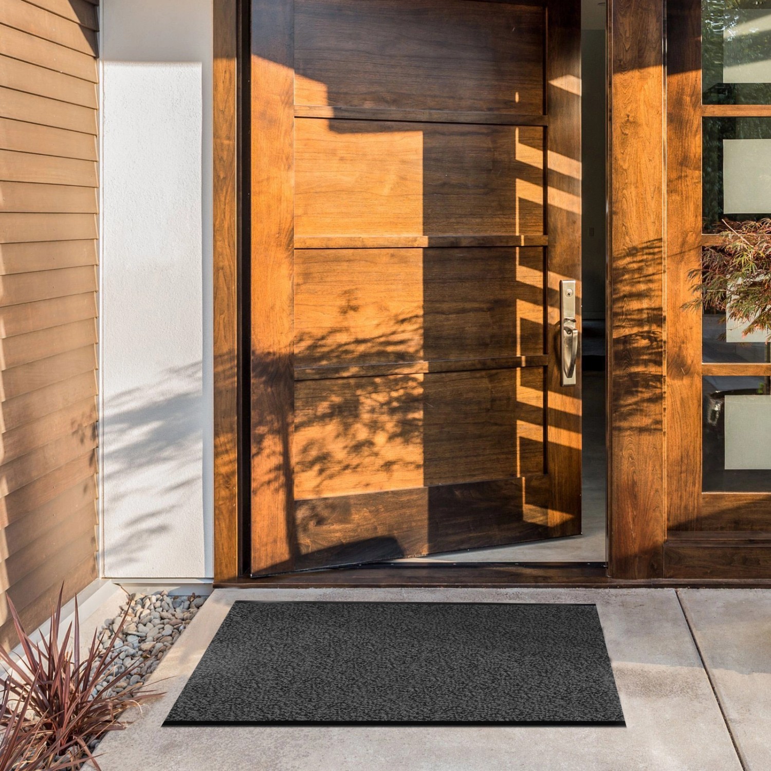 Anthrazitfarbene KARAT Schmutzfangmatte SKY nach Maß (120x100 cm) vor einer Holztür.