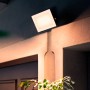 Quadratischer, schwarzer Philips LED-Außenstrahler Lois mit warmweißem Licht an einer Wand.