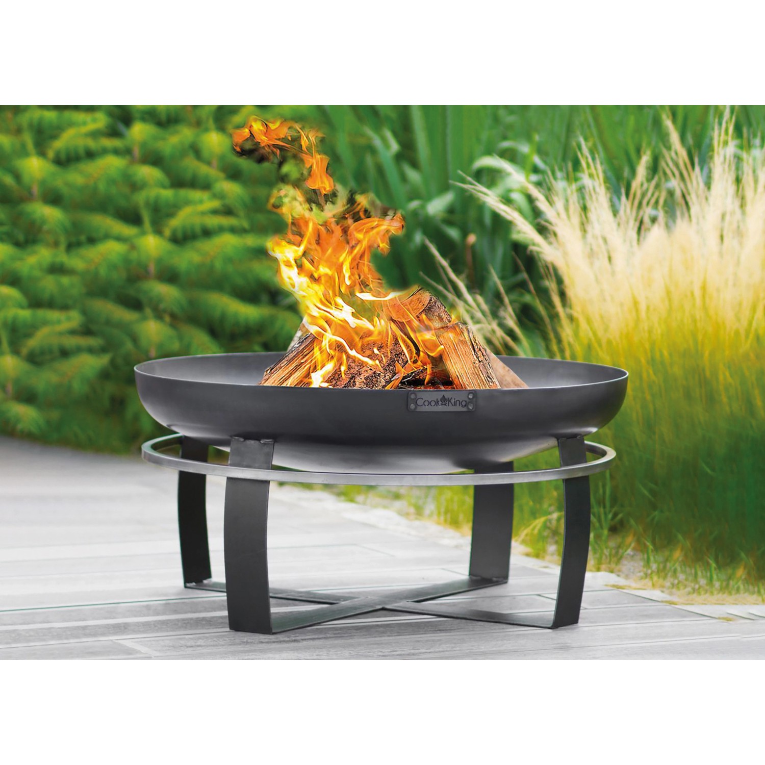 Wilk Feuerschale Viking, Ø 60cm, mit brennendem Holz auf einem Gartensitzplatz.