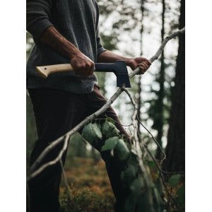 Mann spaltet Ast mit Fiskars Universalaxt im Wald. Axt mit hellem Holzstiel und dunkler Klinge für Holzbearbeitung.