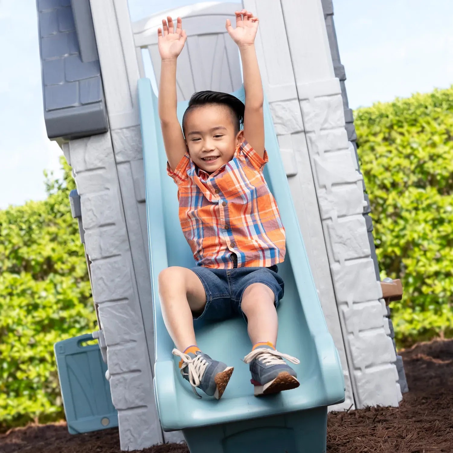 Kind rutscht auf der Rutsche des Step2 Spielhaus Adventures mit 2 Etagen herunter.