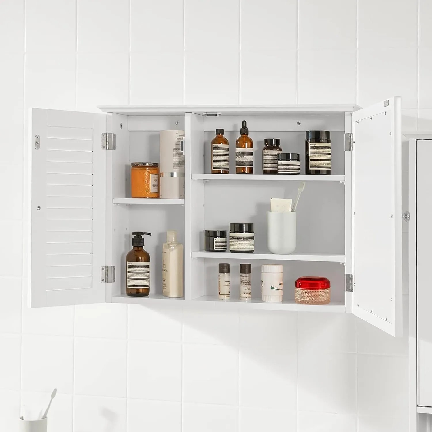 SoBuy Spiegelschrank BZR55-W, weißer Hängeschrank mit Lamellentür, geöffnet und mit Badutensilien gefüllt.