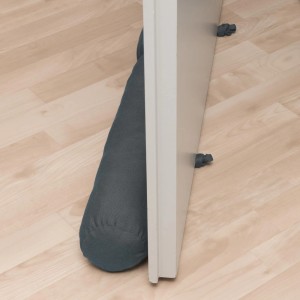 Beautissu Viento Zugluftstopper, 10x100cm, Anthrazit, vor Tür auf hellem Holzboden.