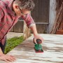 Mann schleift mit Bosch Akku-Multischleifer UniversalSander 18V-10 eine Holzplatte. Grüner Deltaschleifer für vielseitige Schleifarbeiten.