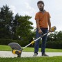 Mann nutzt Stiga Akku-Rasentrimmer GT 500e zum Kantenschneiden im Garten. Inkl. Akku und Ladegerät.