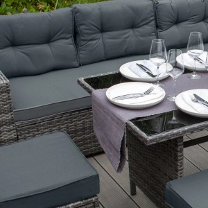 Graues Polyrattan Gartenmöbel Set mit Tisch, Sofa, Hockern und grauen Polstern.