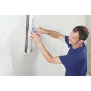 Mann glättet Wand mit Knauf Multifinish Spachtelmasse und Werkzeug. Zubehör für Gipskartonplatten.