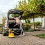 Frau saugt mit Kärcher WD 5 V-25/5/22 Nass-/Trockensauger Kofferraum eines Autos.