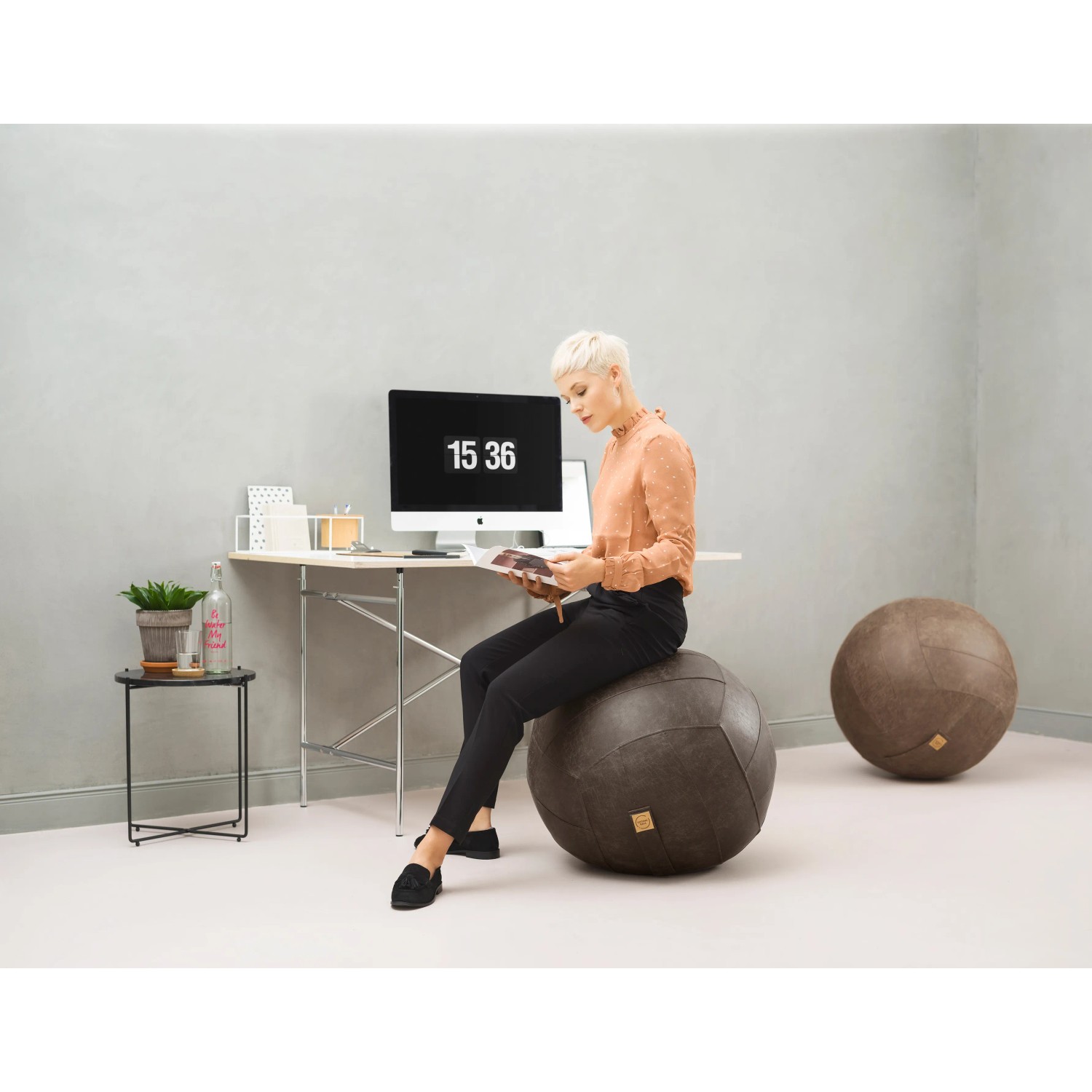 Frau sitzt auf anthrazitfarbenem Sitting Ball Hocker Frankie 150l im Wohnraum.
