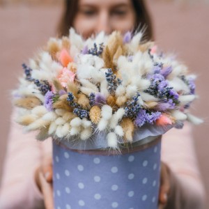 Rundes Gesteck aus bunten Trockenblumen in gepunkteter Box, gehalten. Zeigt Anwendung von Steckschaum für kreative Gestecke.