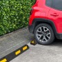 UvV Ecopark Radstopper in Schwarz-Gelb vor einem roten Auto auf einem Parkplatz.
