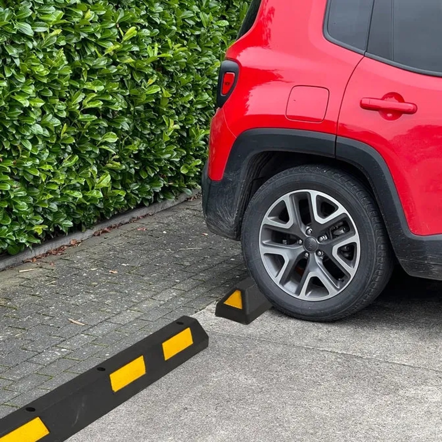 UvV Ecopark Radstopper in Schwarz-Gelb vor einem roten Auto auf einem Parkplatz.