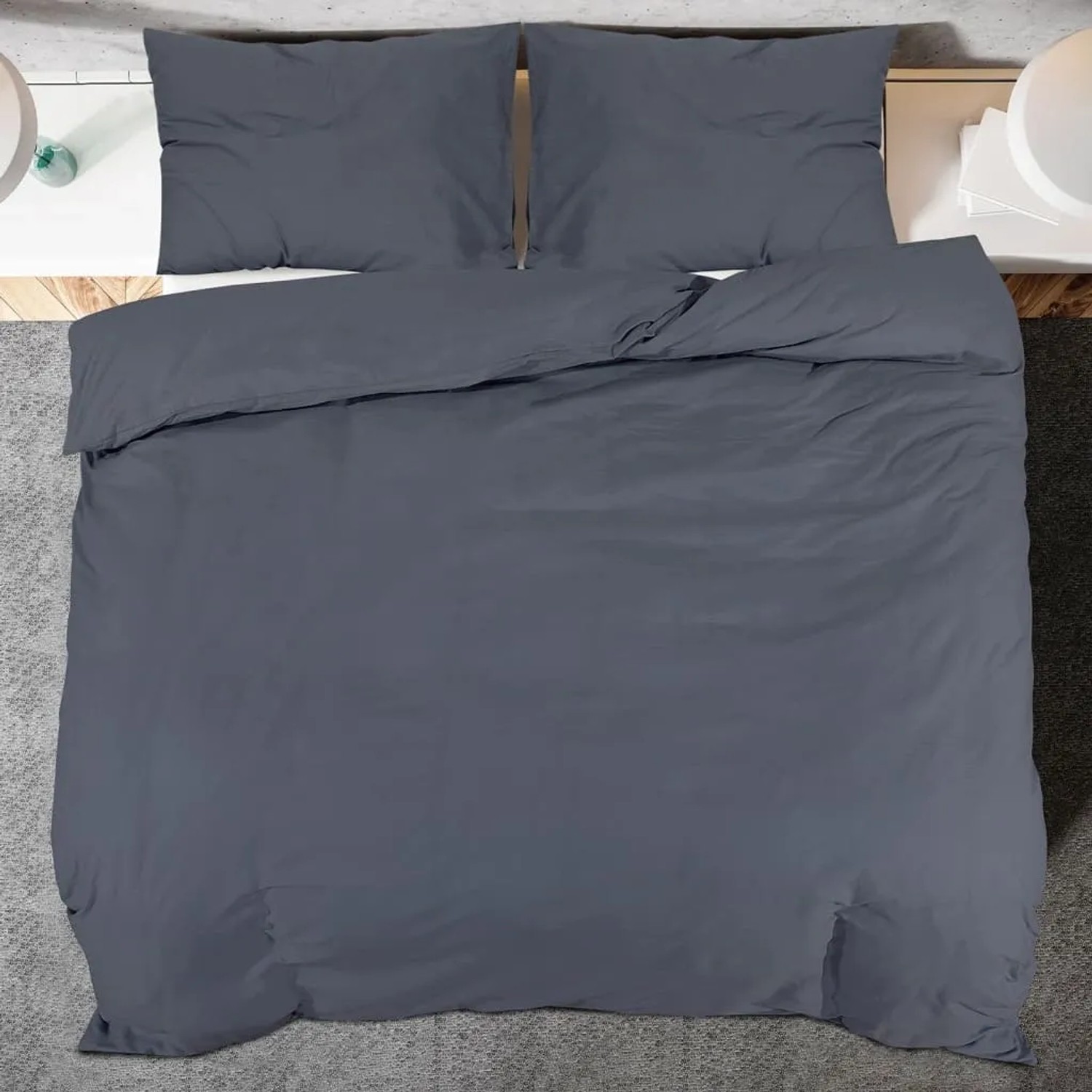 Anthrazitfarbenes Baumwoll-Bettwäsche-Set mit Deckenbezug und zwei Kissenbezügen, auf einem Bett ausgebreitet.