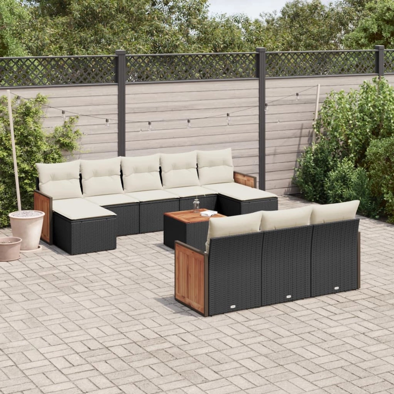 vidaXL 11-tlg. Garten-Sofagarnitur aus schwarzem Poly Rattan mit cremeweißen Kissen auf einer Terrasse.