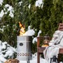 Feuerhand Pyron Feuertonne aus Edelstahl (25 l) im Garten mit brennendem Feuer und Holzscheiten.