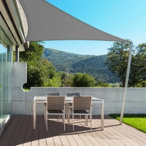 Graues, dreieckiges Karat Sonnensegel über einer Terrasse mit Tisch und Stühlen. Atmungsaktiver UV-Schutz.