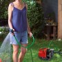 Frau bewässert Garten mit Einhell Hauswasserautomat GC-AW 6033.